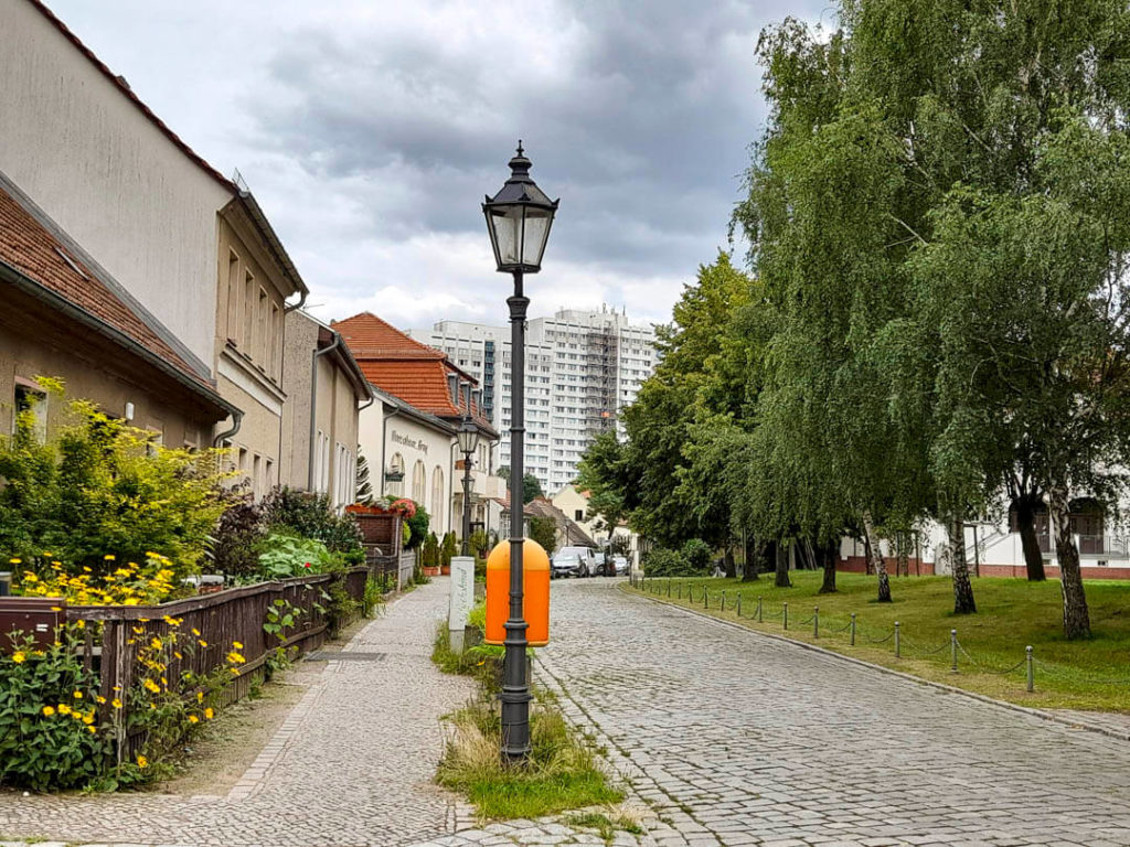 Foto des Dorfkerns Alt-Marzahn in Berlin, am Horizont ein Plattenbau