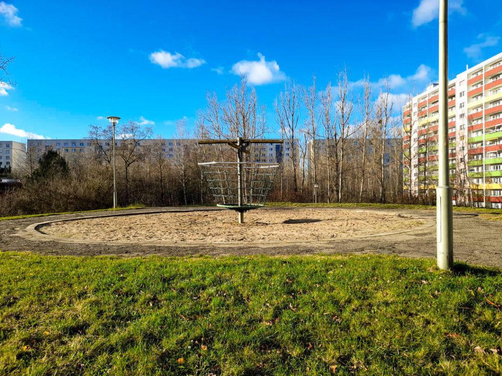 Foto: Spielplatz auf einer erhöhten Grünfläche in Marzahn, dahinter Plattenbauten