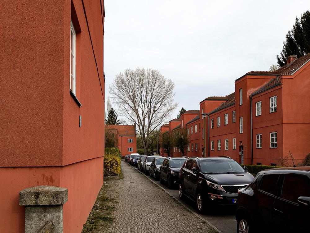 Foto der Splanemannsiedlung in Berlin, zu sehen ist ein Abschnitt der Splanemannstraße mit den roten, zweigeschossigen Gebäuden
